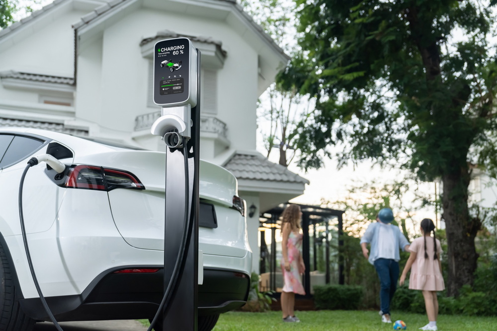 Focus EV station recharging battery for EV car on blurred family. Synchronos